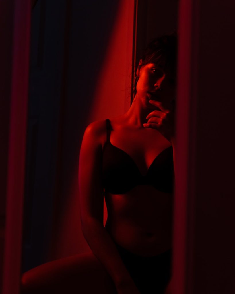 woman in black brassiere standing near red curtain
